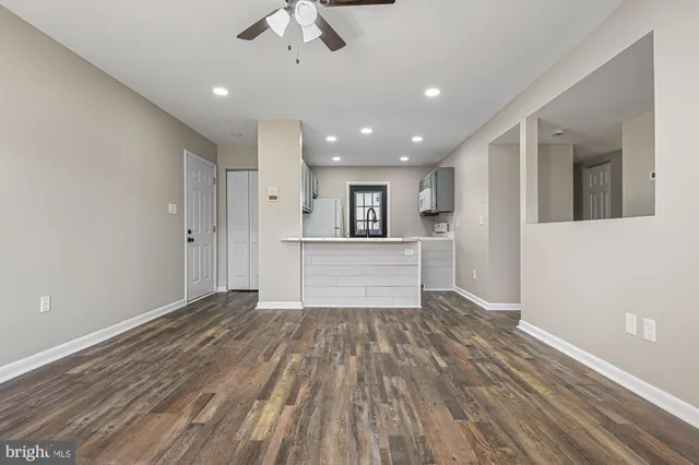 a view of kitchen and empty room with wooden floor