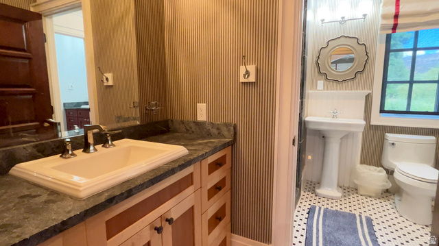 426 West Center Street Parowan, UT 84761 - Photo 52 of 107 Two distinct vanity areas featuring a light wood-finish vanity with a dark stone countertop and an undermount sink, alongside a classic pedestal sink