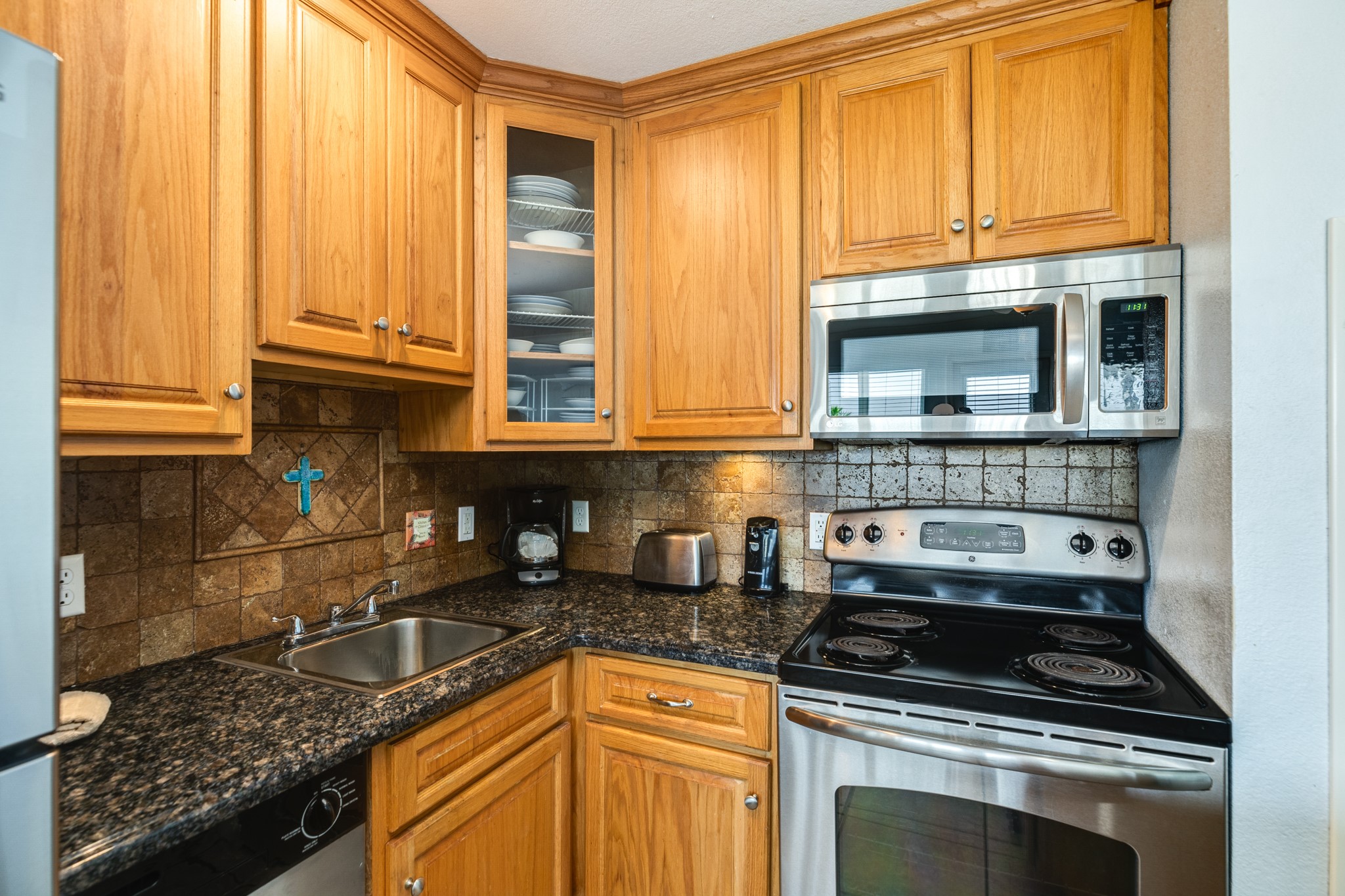 10811 Termini-San Luis Pass Road, Unit 1201 Galveston, TX 77554 - Photo 13 of 25 a kitchen with stainless steel appliances granite countertop a stove a sink and a microwave