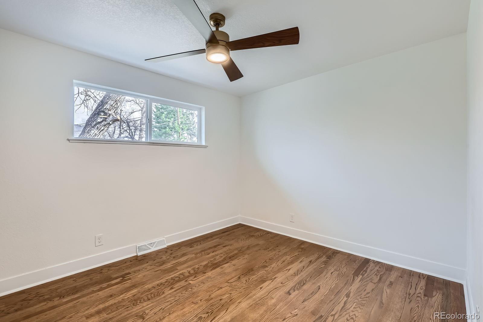9455 West 37th Avenue Wheat Ridge, CO 80033 - Photo 20 of 33 an empty room with wooden floor ceiling fan and window