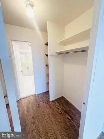 a view of a hallway with wooden floor and a cabinet