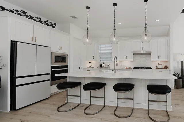 a kitchen with stainless steel appliances a stove a sink island and a refrigerator with wooden floor