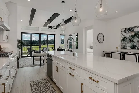a kitchen with stainless steel appliances granite countertop a stove and a view of living room
