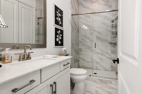 a bathroom with a granite countertop sink a toilet and shower