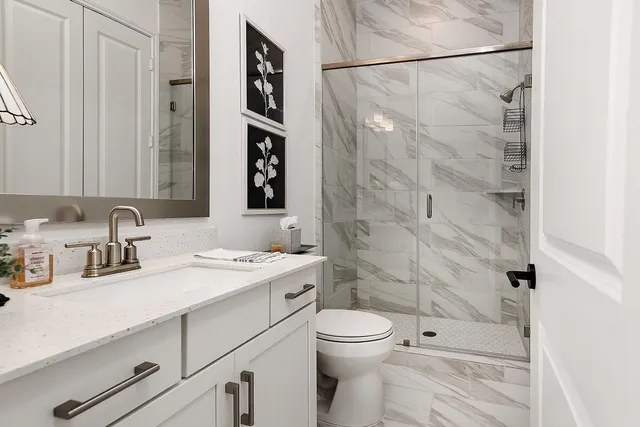 a bathroom with a granite countertop sink a toilet and shower