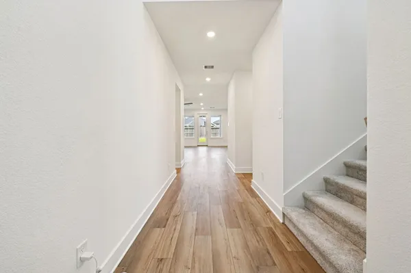 a view of a hallway with wooden floor and staircase