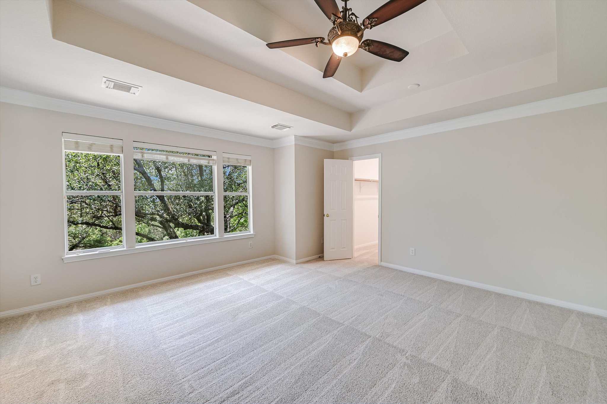 2849 Grimes Ranch Road Austin, TX 78732 - Photo 18 of 31 A spacious primary bedroom features tray ceilings and ample natural light through expansive windows.