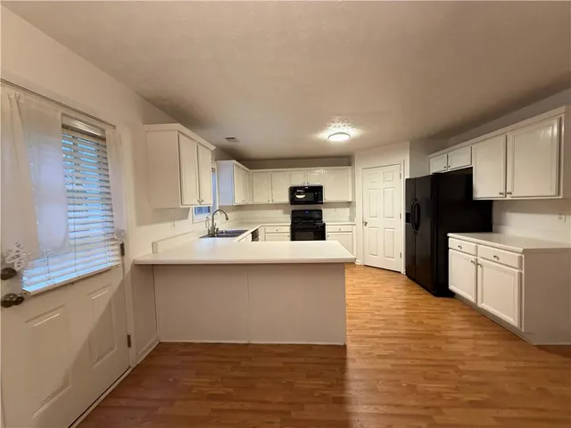 a kitchen with stainless steel appliances a sink a stove a refrigerator cabinets and a window