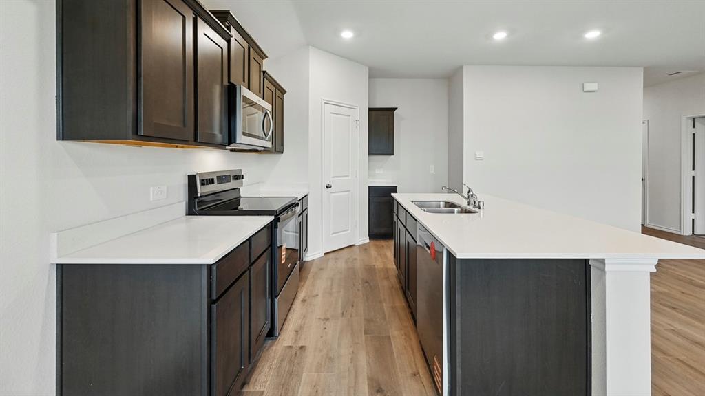 511 Lantana Road Princeton, TX 75407 - Photo 20 of 35 a kitchen with stainless steel appliances a sink a microwave oven and a refrigerator with wooden floor