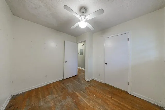 an empty room with wooden floor and ceiling fan