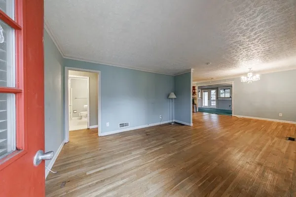 a view of an empty room with window and wooden floor