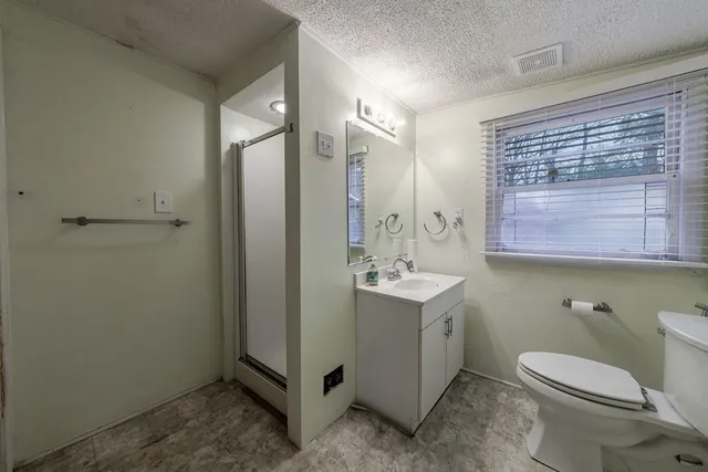 a bathroom with a granite countertop toilet a sink and a mirror