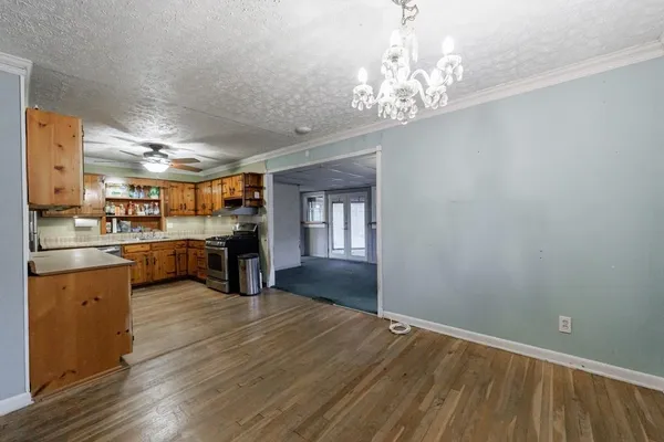 a kitchen with stainless steel appliances granite countertop a stove top oven a sink dishwasher and a refrigerator with wooden floor