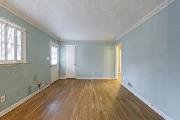 an empty room with wooden floor and windows
