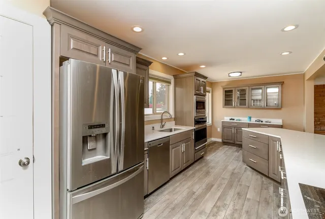 a large kitchen with stainless steel appliances granite countertop a refrigerator and a stove top oven