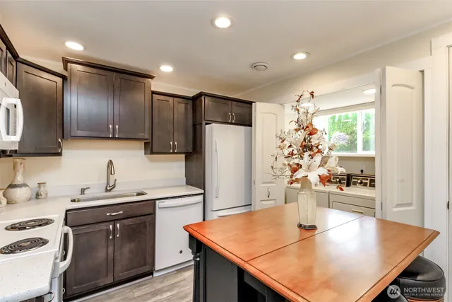 a kitchen with stainless steel appliances granite countertop a refrigerator a sink a stove a dining table and chairs