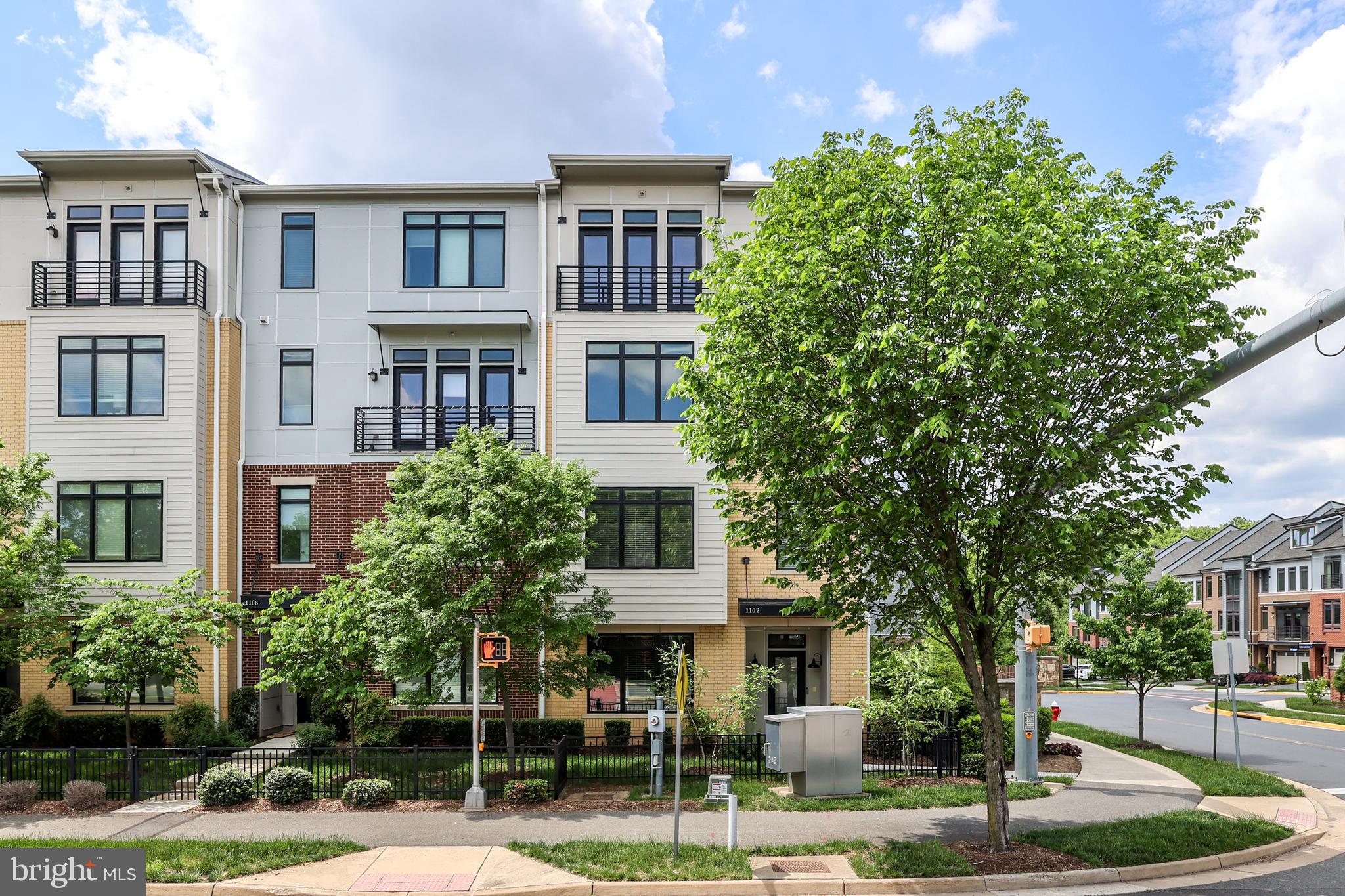 a front view of a residential apartment building with a yard and potted plants