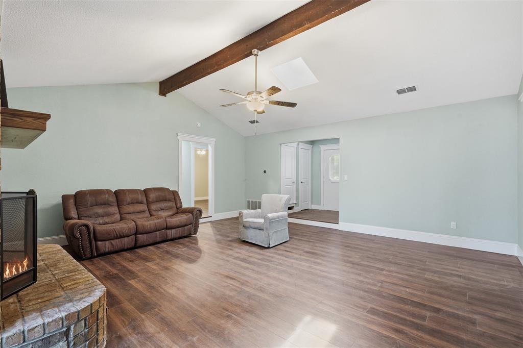 104 Murls Lake Road Weatherford, TX 76085 - Photo 10 of 39 Vaulted ceiling with exposed wood beam, wood-finish flooring, brick fireplace with wood mantel, ceiling fan with light fixture, and white baseboards