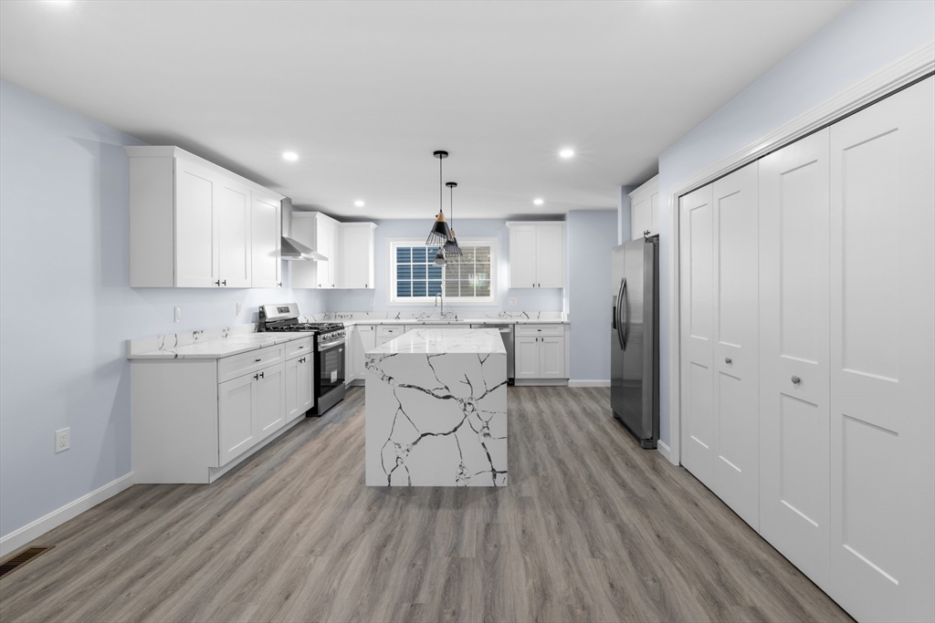 75 Hunter Street Fall River, MA 02721 - Photo 2 of 14 a kitchen with stainless steel appliances kitchen island granite countertop a refrigerator a sink dishwasher and white cabinets with wooden floor