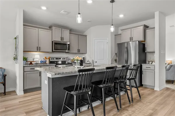 a kitchen with kitchen island granite countertop a table chairs microwave and refrigerator