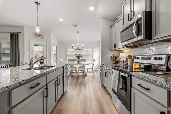 a kitchen with stainless steel appliances granite countertop a sink a stove and a wooden floors