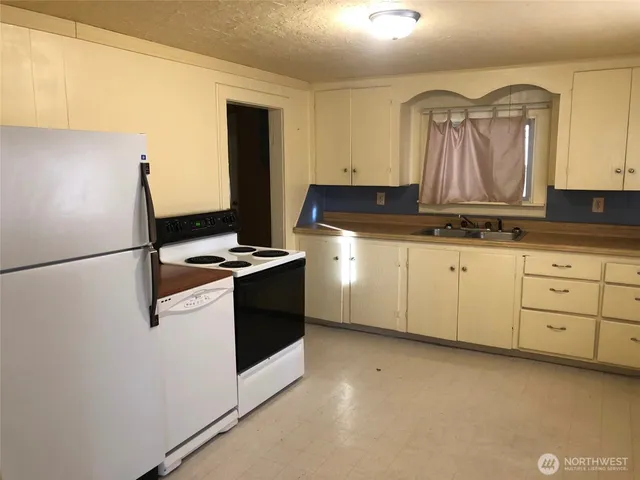 a kitchen with granite countertop a sink stove and cabinets
