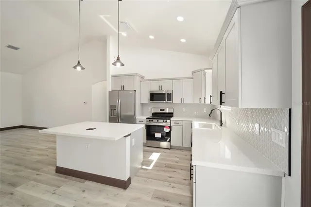 a large white kitchen with stainless steel appliances