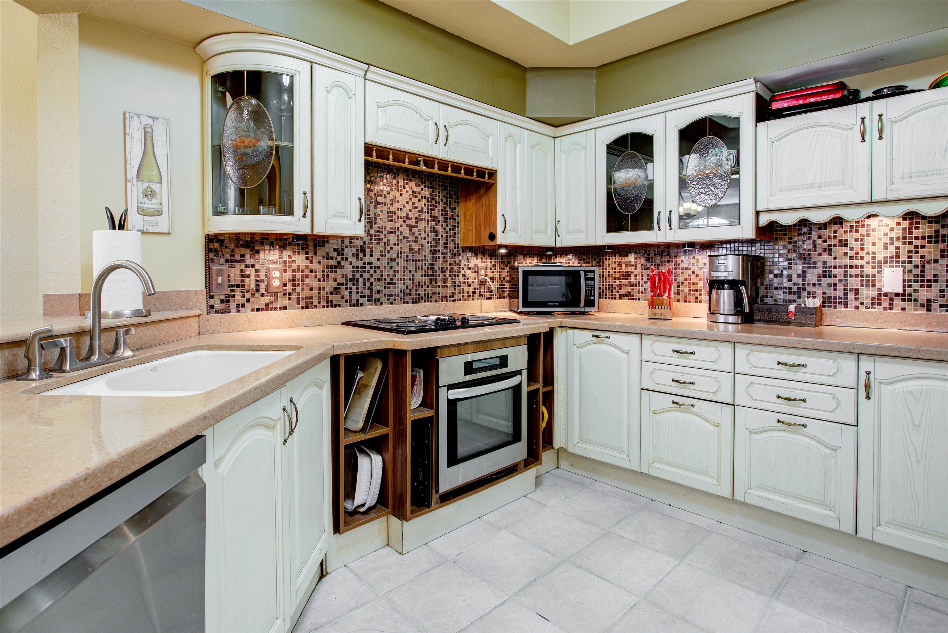 1800 Vista Cove Road St. Augustine, FL 32084 - Photo 16 of 69 Kitchen with glass fronted cabinets, light stone countertops, stainless steel appliances, and white cabinetry