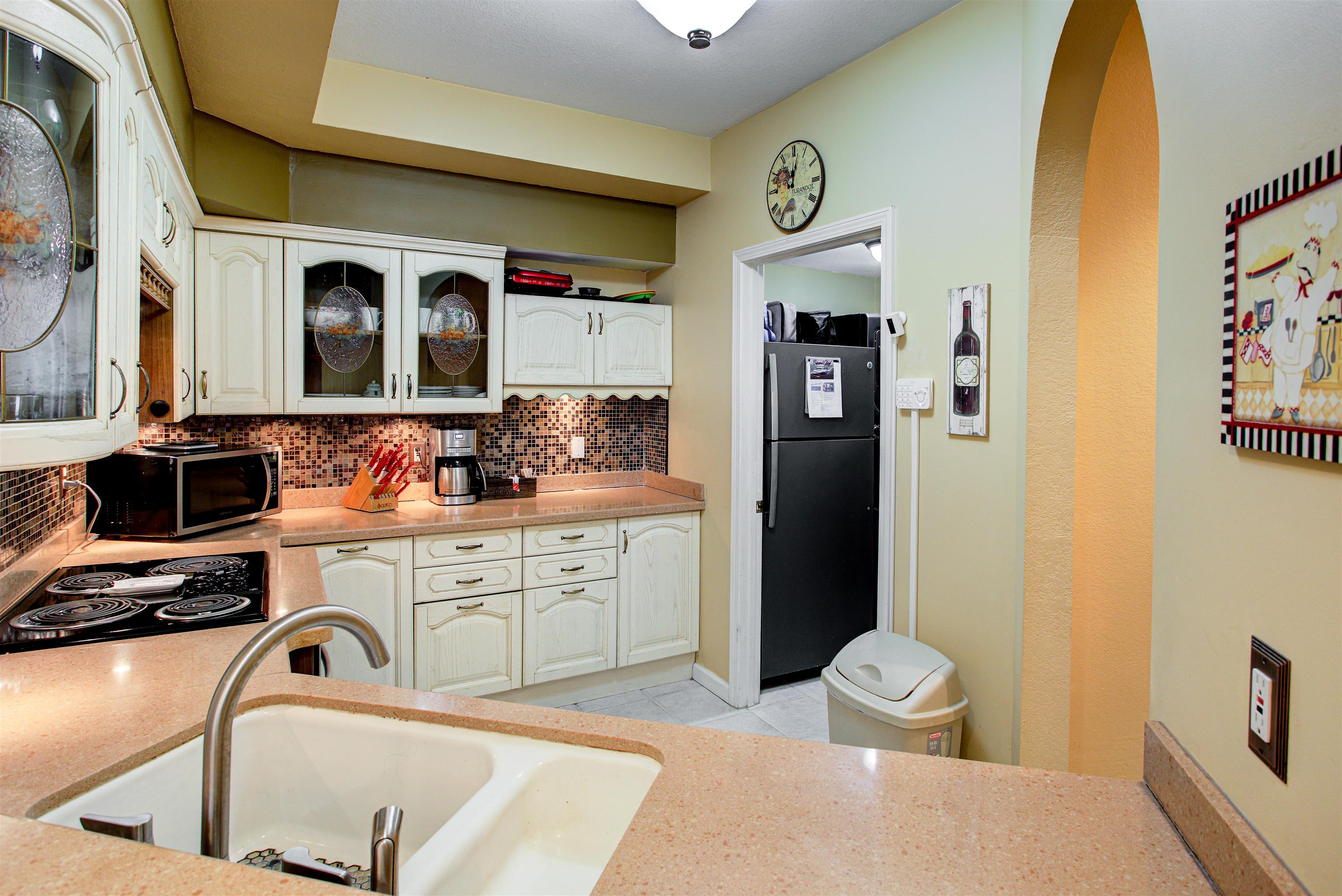 1800 Vista Cove Road St. Augustine, FL 32084 - Photo 17 of 69 Kitchen featuring white cabinets, freestanding refrigerator, glass fronted cabinets, and backsplash