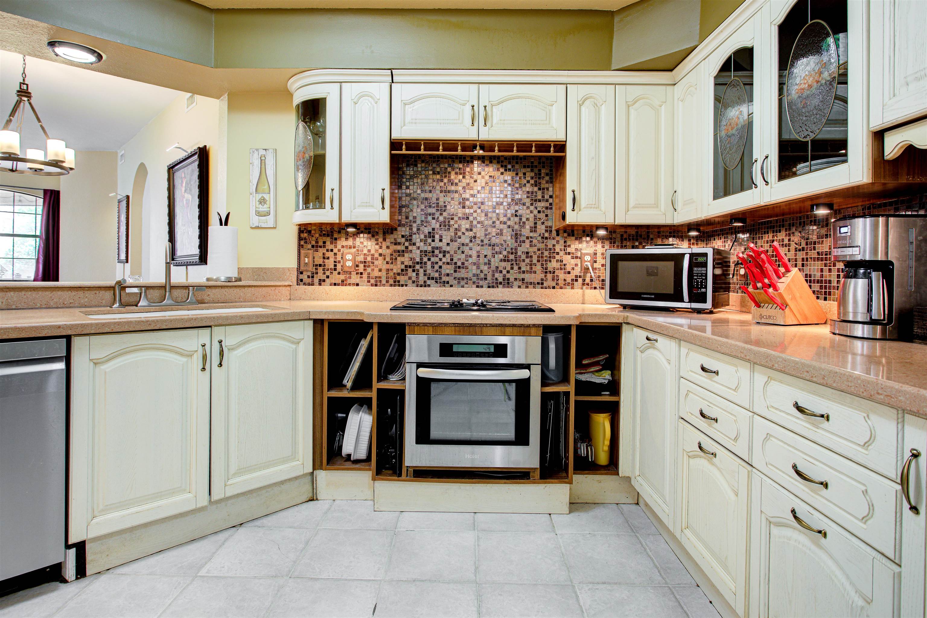 1800 Vista Cove Road St. Augustine, FL 32084 - Photo 20 of 69 Kitchen featuring glass fronted cabinets, stainless steel appliances, light stone counters, decorative backsplash, and suspended lighting