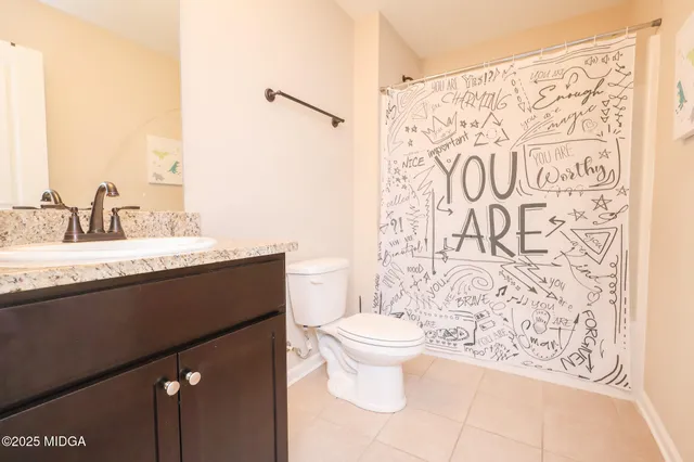 a bathroom with a granite countertop sink and a toilet