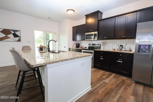 a kitchen with granite countertop a sink cabinets and stainless steel appliances