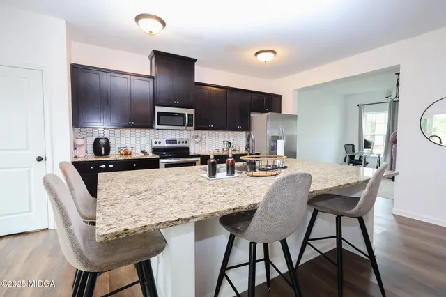 a kitchen with granite countertop a table chairs microwave and cabinets
