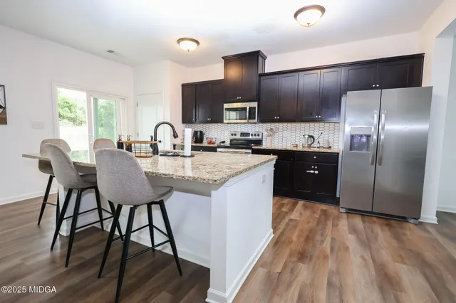 a kitchen with kitchen island granite countertop a sink cabinets and wooden floor