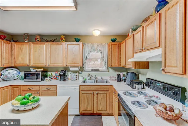 a kitchen with stainless steel appliances granite countertop a sink a stove and a wooden cabinets