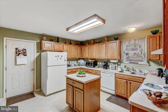 a kitchen with a refrigerator a stove a sink dishwasher and wooden cabinets with wooden floor