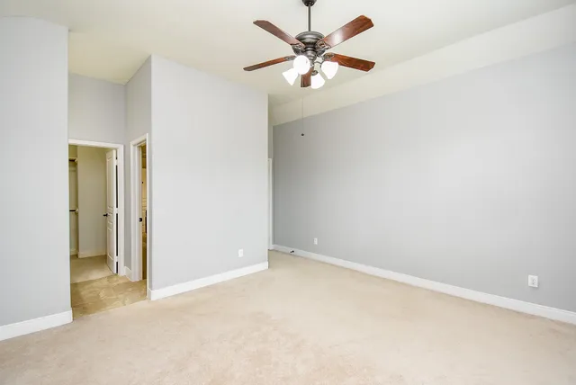 an empty room with a chandelier fan and a bathroom