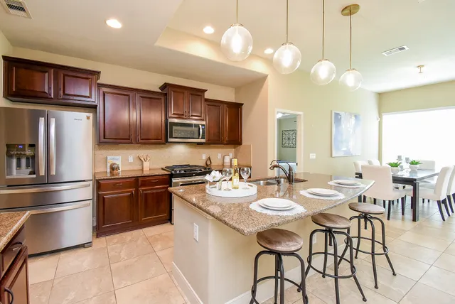 a kitchen with stainless steel appliances granite countertop a stove a sink dishwasher a dining table and chairs with wooden floor