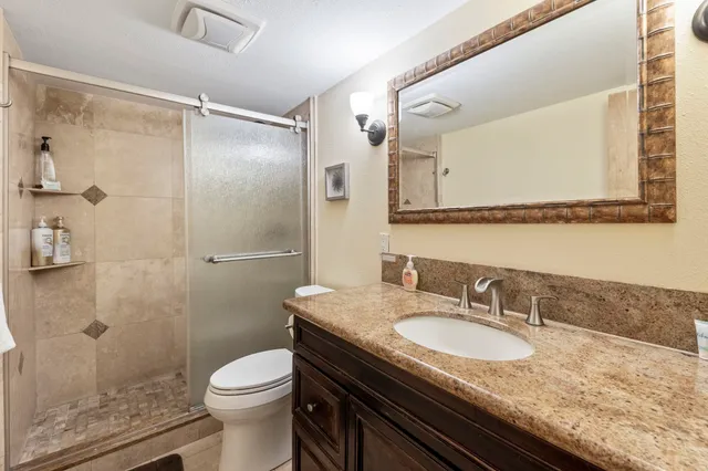 a bathroom with a granite countertop sink a mirror and a toilet