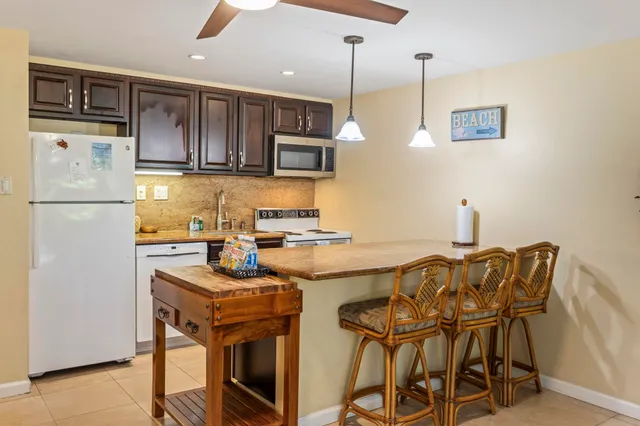 a kitchen with stainless steel appliances granite countertop a stove top oven a refrigerator a sink and chairs