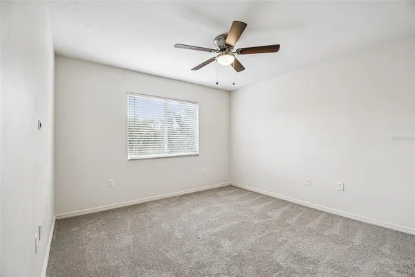 an empty room with a window and a fan