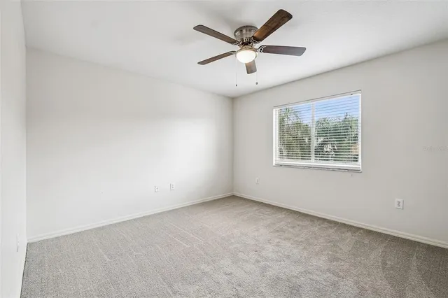 an empty room with a window and a ceiling fan