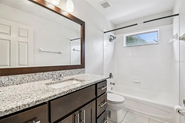 a bathroom with a granite countertop sink a toilet a mirror and bathtub