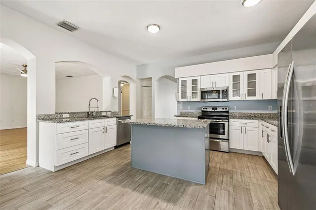 a kitchen with stainless steel appliances granite countertop a stove a sink dishwasher a refrigerator and a oven with wooden floors