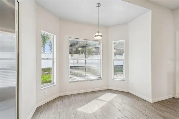 a view of an empty room with a window and hardwood floor