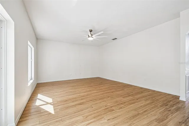 an empty room with wooden floor and ceiling fan