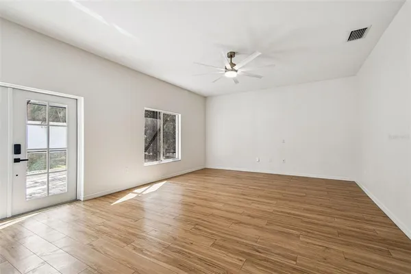 a view of an empty room with a window and wooden floor