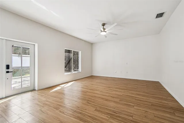 a view of an empty room with a window and wooden floor