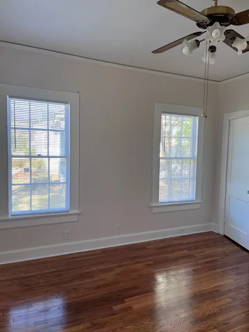 an empty room with wooden floor chandelier fan and window