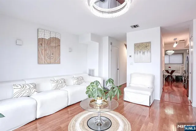 a kitchen with stainless steel appliances a sink dishwasher stove and white cabinets with wooden floor